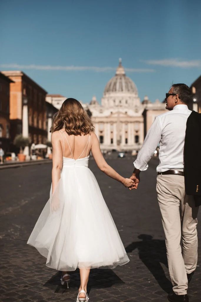 A couple walking towards San Pietro Basilica after a wedding at Campidoglio.