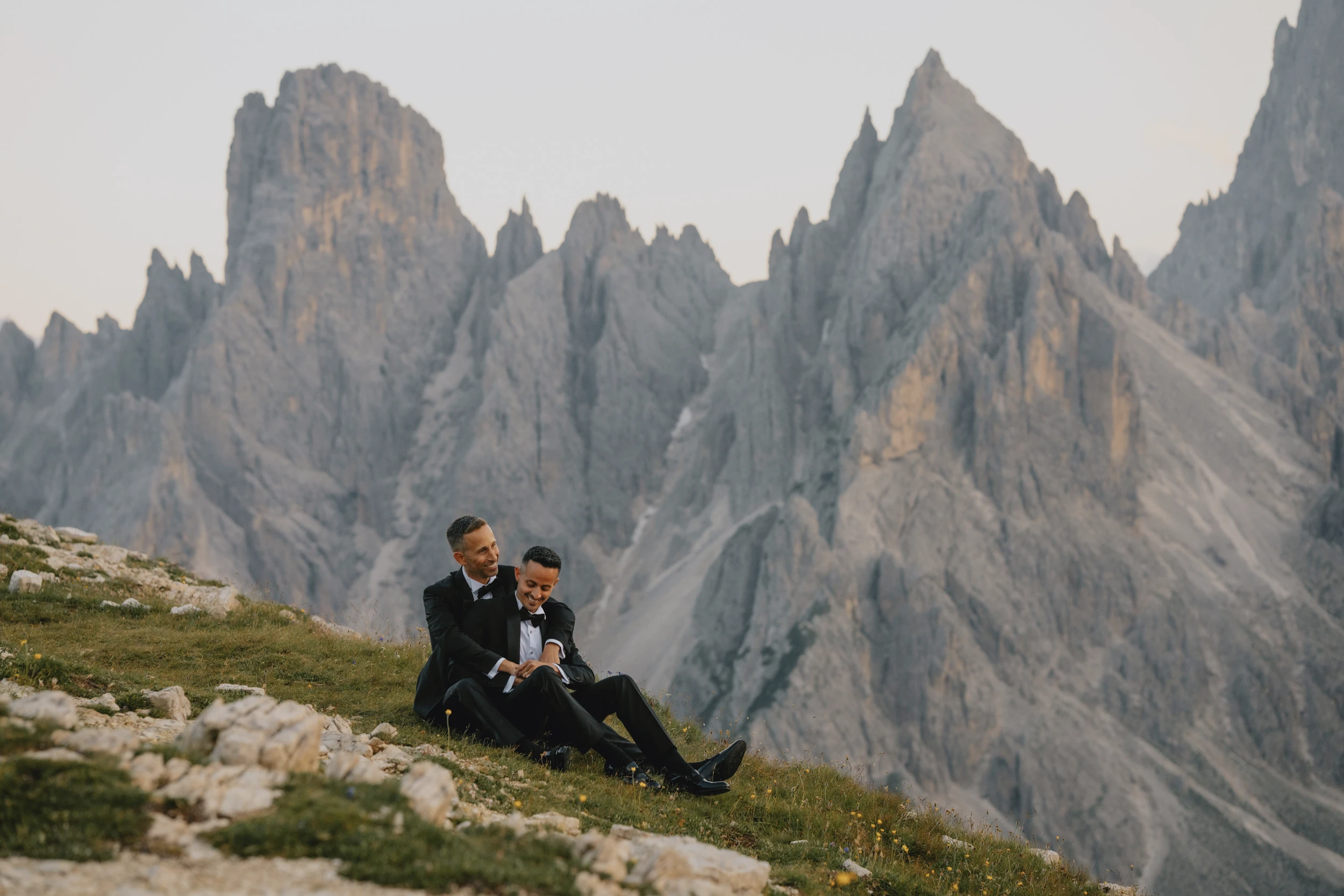A gay couple sitting at Cadini di Misurina in the Dolomites before their wedding.