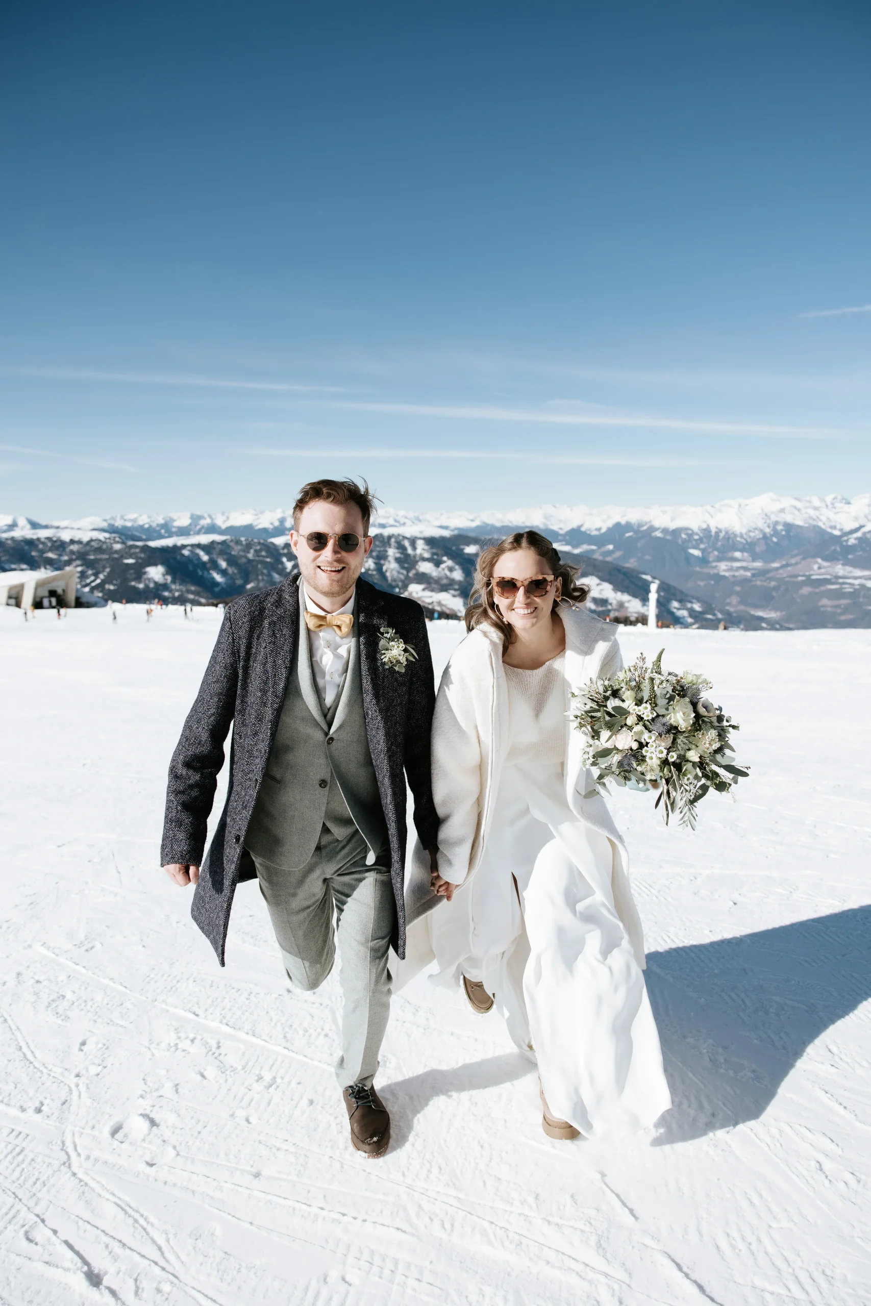 Newlywed couple walking together in the snow.