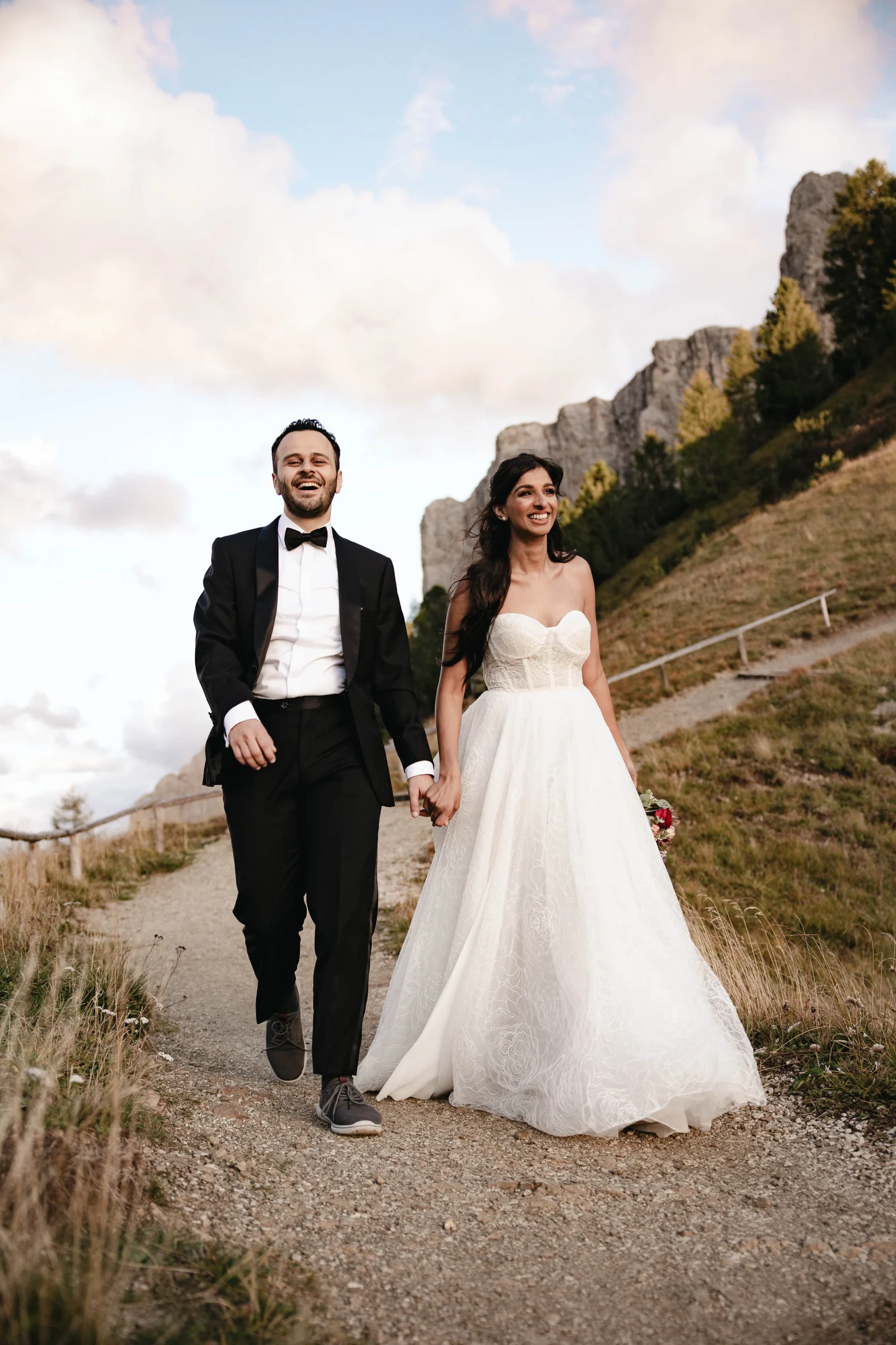 A newlywed couple walks down to a path.